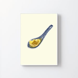 May include: A blue and white porcelain spoon with a yellow dumpling inside. The spoon is on a light yellow background.