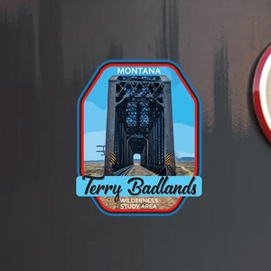 May include: A Montana vinyl decal featuring a detailed illustration of the Terry Badlands Wilderness Study Area bridge. The sticker is in a blue, red, and white design, with the text "Terry Badlands" and "Montana". A second decal reads "Stuck On Travel, Vinyl Decals, Travel Memories".