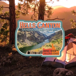 May include: A scenic image of Hells Canyon National Recreation Area, featuring a river winding through a canyon. The image includes a tent, trees, and the text "Hells Canyon National Recreation Area" and "Snake River Oregon & Idaho."