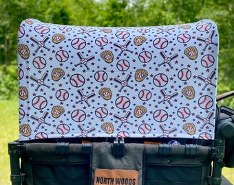May include: A black wagon with a white canopy featuring a baseball themed pattern. The canopy has red stars, baseballs, bats, and gloves. The wagon has a brown leather patch with the text "NORTH WOODS crafting co."