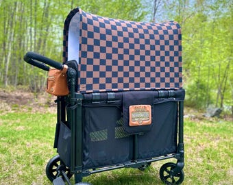 Op de afbeelding: Een zwarte wagen met een bruin en zwart geruit zonnedak. De wagen heeft een zwarte mesh-opslagruimte en een bruine leren tas aan de handgreep. De wagen heeft een "Wagon Nation Threads" logo aan de zijkant.