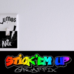 May include: A white light switch cover with a black and white graphic of a lightning bolt. The words "Lumos" and "Nox" are printed on the cover. The cover is designed to look like a light switch.