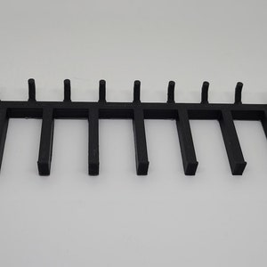 以下が含まれることがあります： 10個のフックが付いた黒い金属製のラック。アイテムを掛けるために設計されています。
