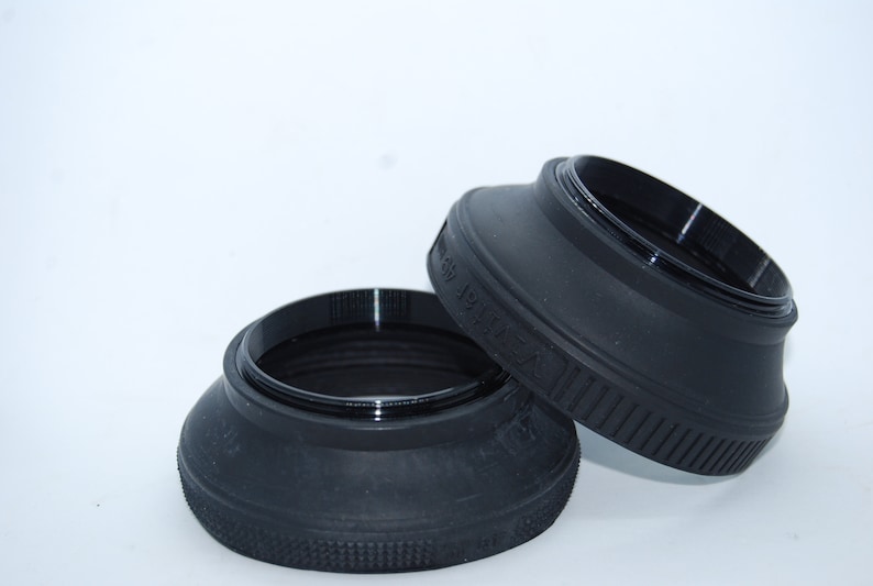 May include: Two black lens hoods for cameras. The hoods are made of rubber and have a textured surface. The larger hood has the text "58mm" printed on it.