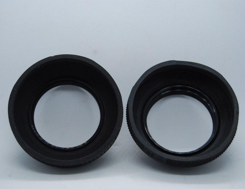 May include: Two black rubber lens hoods for camera lenses.