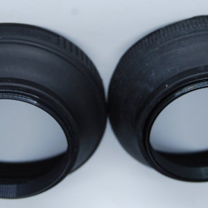 May include: Two black rubber lens hoods for a camera lens. The hoods are designed to block out stray light and glare.