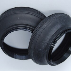 May include: Two black rubber lens hoods for a camera. The hoods are designed to block out unwanted light and glare.