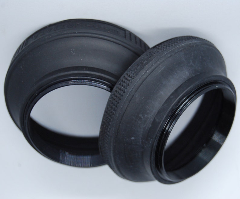 May include: Two black rubber lens hoods for a camera. The hoods are designed to block out unwanted light and glare.