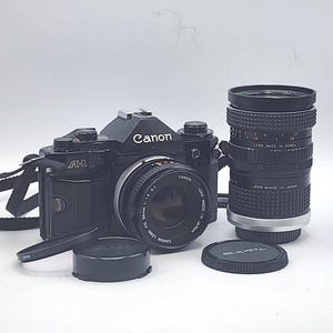 Canon A-1 Black Slr Film Camera w/ Canon FD 50mm f1.8 S.C., Aqunon Automatic f2.8 28mm Lens, MC Tokina Doubler for C/FD