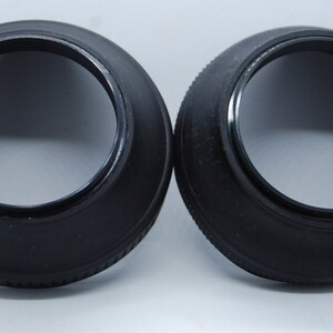 May include: Two black lens hoods for camera lenses. The hoods are made of a rubber-like material and have a smooth, black finish.