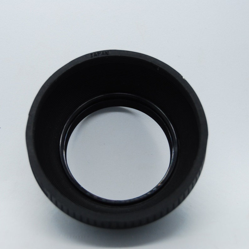 May include: Black rubber lens hood with the word "JAPAN" printed on the top.
