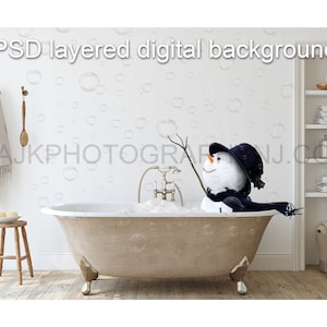 May include: A snowman wearing a black hat and scarf is sitting in a white bathtub filled with bubbles. The bathtub has gold feet and is in a white bathroom with a white tiled floor. There is a wooden stool with a white towel on it and a white shelf with towels and other items on it.