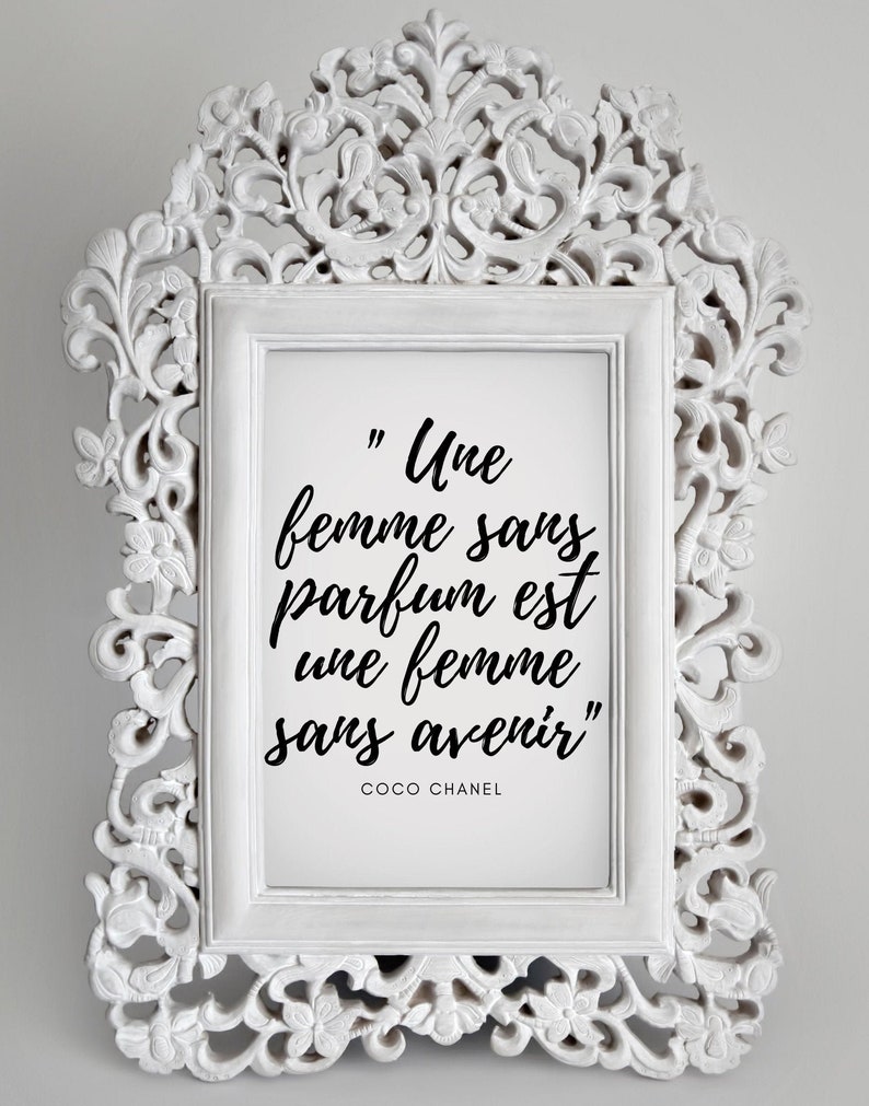 May include: A white ornate frame with a black and white print inside. The print features a quote in French by Coco Chanel: "Une femme sans parfum est une femme sans avenir".
