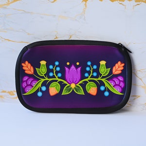 May include: A purple zippered pouch with a floral design featuring a pink flower, green leaves, orange and blue berries, and yellow accents.