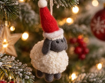 May include: A felted wool sheep ornament featuring a cream-colored textured body, dark gray ears and legs, and a bright red Santa hat with a white pom-pom and trim. The ornament hangs from a thin string loop, showcasing a soft, handcrafted appearance.