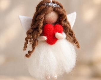 May include: A needle-felted angel ornament with long brown yarn hair, a small clear bead halo, and white felt wings. The figure wears a fluffy white skirt, holds a bright red heart, and has two small white beads for feet.