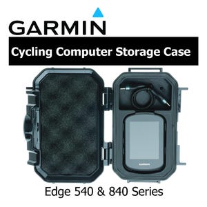 May include: Black Garmin cycling computer storage case, open to reveal a cycling computer and accessories. The case is labeled "Edge 540 & 840 Series" and has the Garmin logo at the top. The case is designed to protect the computer.