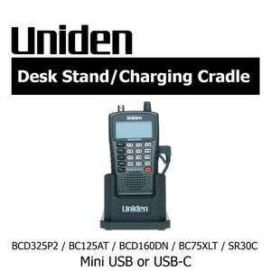 Puede incluir: Un soporte de escritorio y base de carga Uniden negro con una radio portátil. La radio tiene una pantalla y varios botones. El texto "Uniden" es visible en la radio y la base. El texto "Desk Stand/Charging Cradle" está encima de la radio.