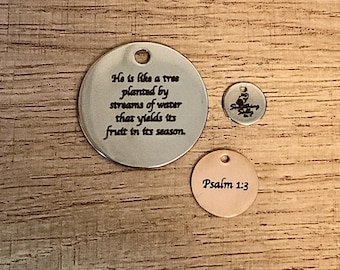 May include: Two silver metal round charms with a bible verse inscription. The larger charm reads "He is like a tree planted by streams of water that yields its fruit in its season." The smaller charm reads "Psalm 1:3".