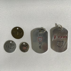 May include: Five silver and gold charms with the state of Ohio engraved on them. The charms are in the shape of a circle and a rectangle. One charm says "Home" with the state of Ohio in red. Another charm says "Y-town" with the state of Ohio. The other charms say "33" and "Yo" with the state of Ohio.