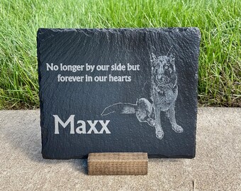 May include: Black slate pet memorial with a white etched image of a German Shepherd dog and the text "No longer by our side but forever in our hearts" and "Maxx".