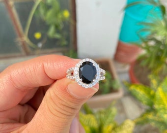 May include: A silver ring with a large black oval gemstone surrounded by smaller white gemstones.