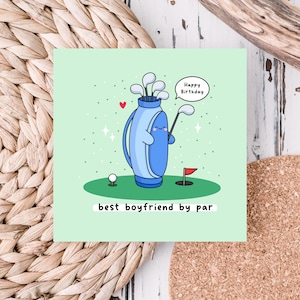 May include: A green card with a cartoon illustration of a golf bag with a happy face and the text "Happy Birthday". The golf bag is holding a golf club and there is a golf ball and a red flag on the green grass. The text "best boyfriend by par" is at the bottom of the card.