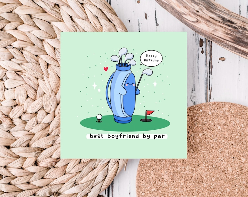 May include: A green card with a cartoon illustration of a golf bag with a happy face and the text "Happy Birthday". The golf bag is holding a golf club and there is a golf ball and a red flag on the green grass. The text "best boyfriend by par" is at the bottom of the card.