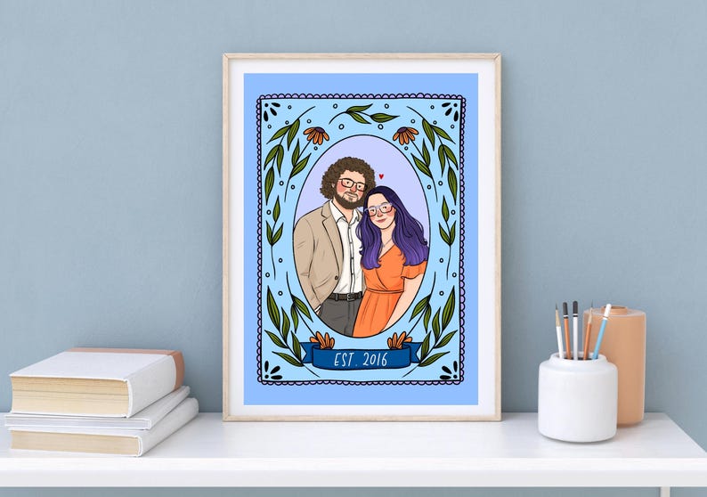 May include: A framed digital illustration featuring a couple inside an oval border decorated with green leaves and orange flowers. The person on the left has curly brown hair and glasses, wearing a tan blazer. The person on the right has long purple hair and glasses, wearing an orange dress. A blue banner at the bottom reads EST. 2016.