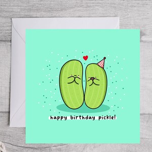 May include: A light green birthday card with two cartoon pickles wearing party hats. The card has the text "happy birthday pickle!" on it.