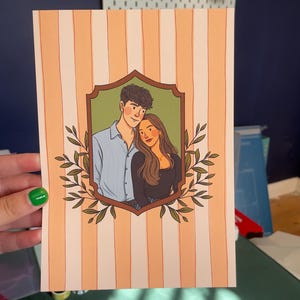 May include: A rectangular art print featuring a vertical peach and white striped background. In the center, a brown ornate frame encloses a digital illustration of two people standing together, surrounded by green leafy branches on both sides.