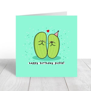 May include: A green birthday card with two cartoon pickles wearing party hats and a red heart above them. The text on the card reads "happy birthday pickle!"