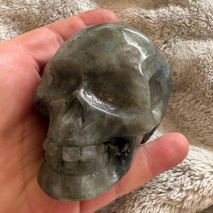 May include: A set of three ceramic mugs with a speckled, matte finish. The mugs are in shades of cream, light gray, and dark gray. Each mug has a simple, minimalist design and a rounded handle. The mugs are stacked on top of each other.