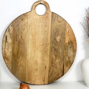 A Beautiful large round solid natural handmade wooden chopping board with carved round  handle.