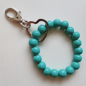May include: A turquoise beaded keychain with a silver heart-shaped charm and a silver clip.