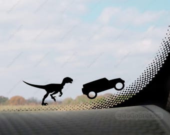 May include: A black silhouette of a dinosaur running away from a black silhouette of a car on a car window. The car window has a black and white dotted pattern.