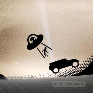 May include: Black sticker featuring a UFO abducting a person from a vehicle. The UFO is above the vehicle, with a beam of light connecting them. The sticker has a minimalist design, with the text "@GoGoStickers" at the bottom.