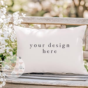 May include: A white pillow with the text "your design here" on a wooden bench with white flowers in the background.