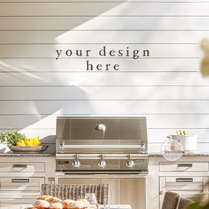May include: A stainless steel outdoor grill with three burners is built into a white wooden outdoor kitchen. The kitchen has two cabinets with white doors and a granite countertop. The grill is in front of a white wood wall with the text "your design here" written on it.