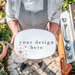 May include: A chef holding a white oval plate with the text "your design here". The chef is wearing a white coat and a striped apron. A grill with vegetables is visible in the background. The Copper South Farm logo is in the lower left corner.