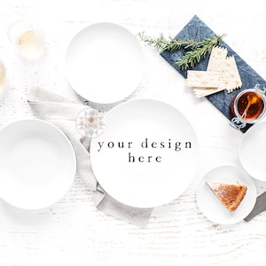 May include: A white table setting with white plates, bowls, and glasses. There is a small plate with a slice of pie and a knife. A slate serving tray with crackers and honey is in the upper right corner. The text "your design here" is written in the center of the image.
