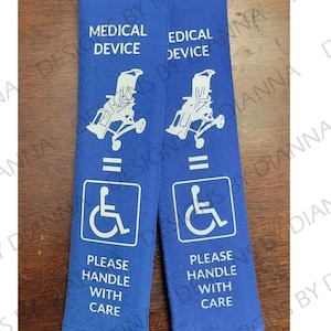 May include: Two blue straps with white text and images. The straps say "Medical Device" and have a wheelchair symbol. The text also says "Please Handle With Care".