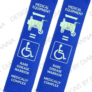 May include: Two rectangular blue fabric covers featuring white text and graphics. Each displays the words MEDICAL EQUIPMENT, a wheelchair icon, RARE DISEASE WARRIOR, and MEDICALLY COMPLEX, with an equals sign between the equipment and icon.