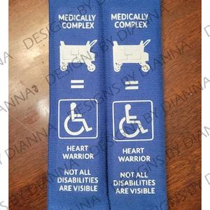 May include: Two blue fabric wristbands with white text. The text reads "Medically Complex", "Heart Warrior", "Not All Disabilities Are Visible", and a wheelchair symbol.