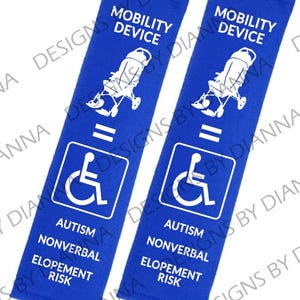 May include: Two blue seatbelt covers with white text and symbols. The text reads "Mobility Device = Autism Nonverbal Elopement Risk". The symbol is a wheelchair.
