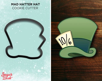 May include: A black cookie cutter in the shape of a Mad Hatter hat. The hat is tall and has a wide brim. The cookie cutter is on a light blue background with white dots.