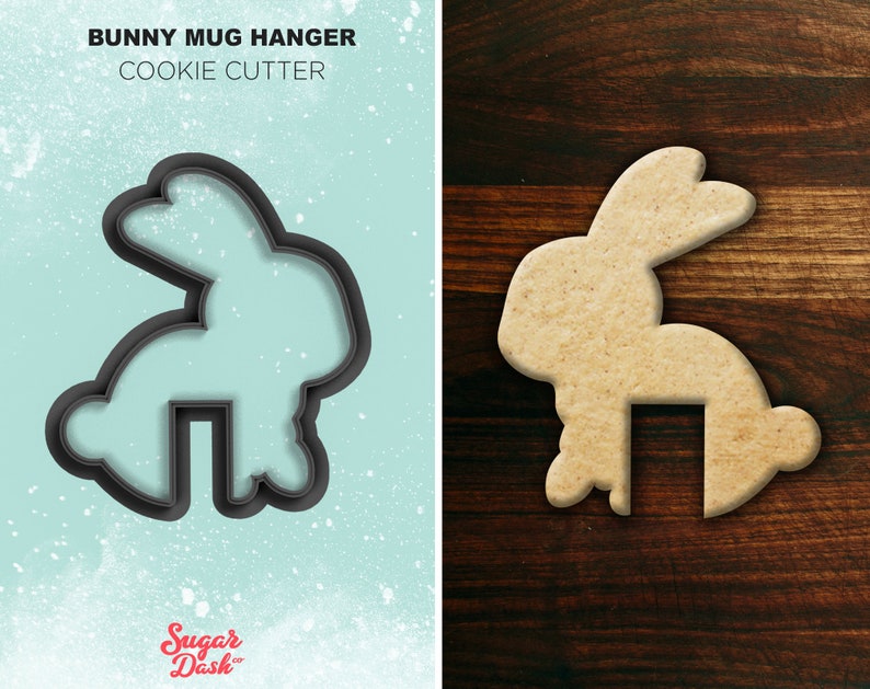 May include: A black cookie cutter in the shape of a bunny rabbit with a cutout for a mug handle. The bunny is standing on its hind legs with its ears up. The cookie cutter is on a light blue background with white speckles. The text "BUNNY MUG HANGER COOKIE CUTTER" is above the cookie cutter. The text "Sugar Dash" is below the cookie cutter.