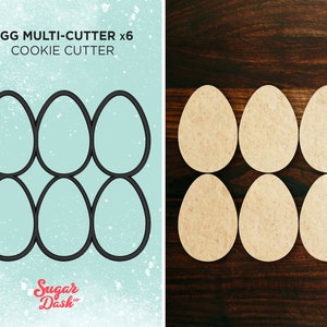 以下が含まれることがあります： 卵の形をしたクッキーカッター6個セット。カッターは金属製で、グリッドパターンに配置されています。カッターは白点のある青い背景の上にあります。画像の上部には「Egg Multi-Cutter x6 Cookie Cutter」というテキストがあります。画像の下部には「Sugar Dash」というテキストがあります。