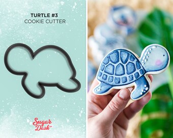 May include: A blue and white turtle cookie cutter with the text "TURTLE #3 COOKIE CUTTER" above it. The image also shows a decorated cookie in the shape of a turtle.
