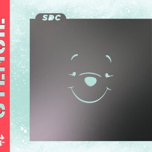 May include: A black stencil with the text "SDC" in the top left corner. The stencil features a simple outline of Winnie the Pooh's face with a smile.